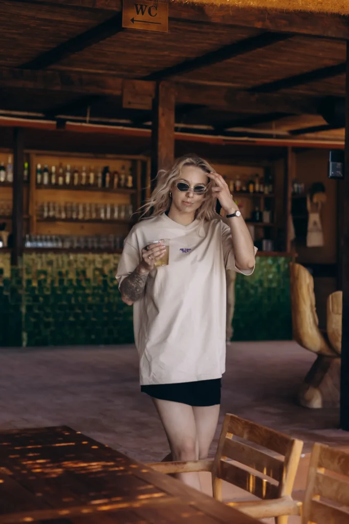 Kobieta w koszulce Miejska Fala z drinkiem w plażowym barze