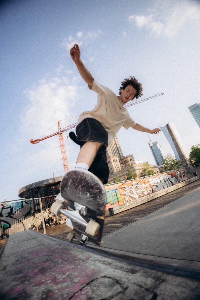 Skater w koszulce Miejska Fala wykonuje trik na deskorolce